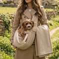 Load image into Gallery viewer, cavapoo puppy being carried in a teddy fleece sling bag by a elegantly dressed woman in the British countryside