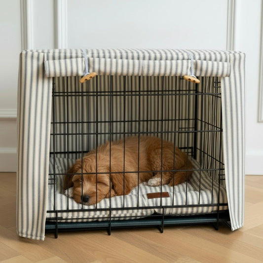 Dog lying inside a black metal crate with striped cover on a wooden floor.