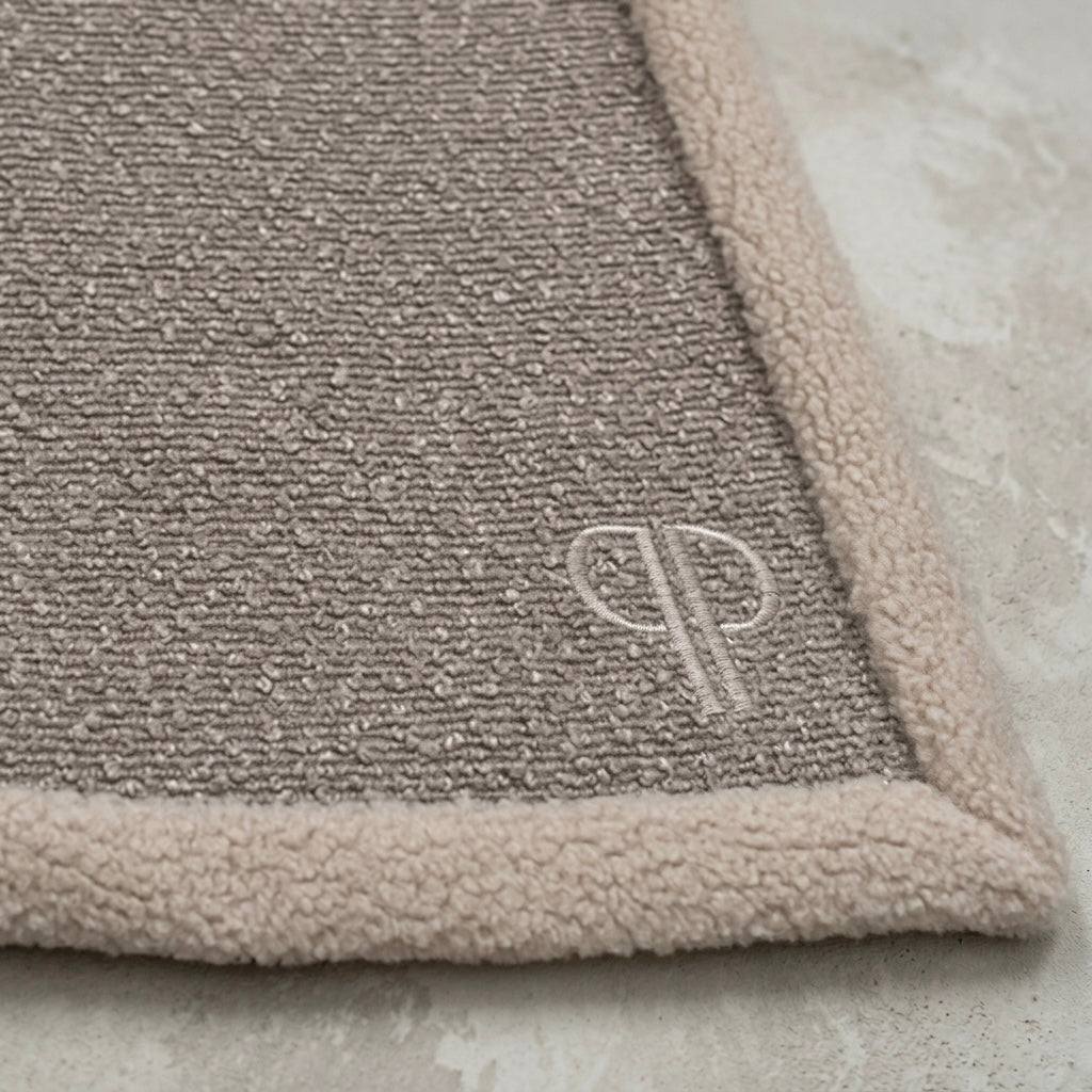 close up of a boucle fabric and sherpa fleece neutral colour blanket with PP monogram 