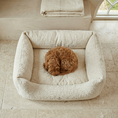 Load image into Gallery viewer, small red maltipoo lying on a boucle dog bed, stone floor and neutral interior 
