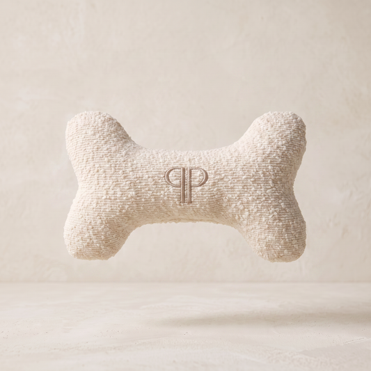 cream boucle fabric go bone toy with embroidery pp monogram on a ivory limewash studio background 