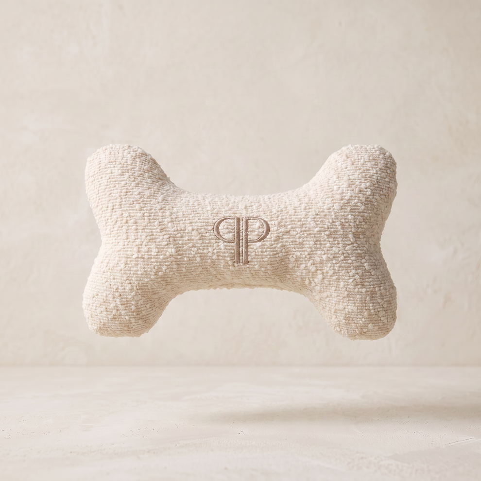 cream boucle fabric go bone toy with embroidery pp monogram on a ivory limewash studio background 