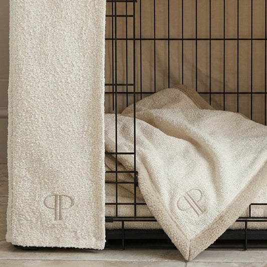 close up of a cream boucle cdog crate set with the coordinating boucle dog blanket with a subtle posh poos PP monogram.