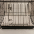 Load image into Gallery viewer, A black metal wire dog crate with a striped taupe and white dog crate mattress bed shown against a neutral light background.

